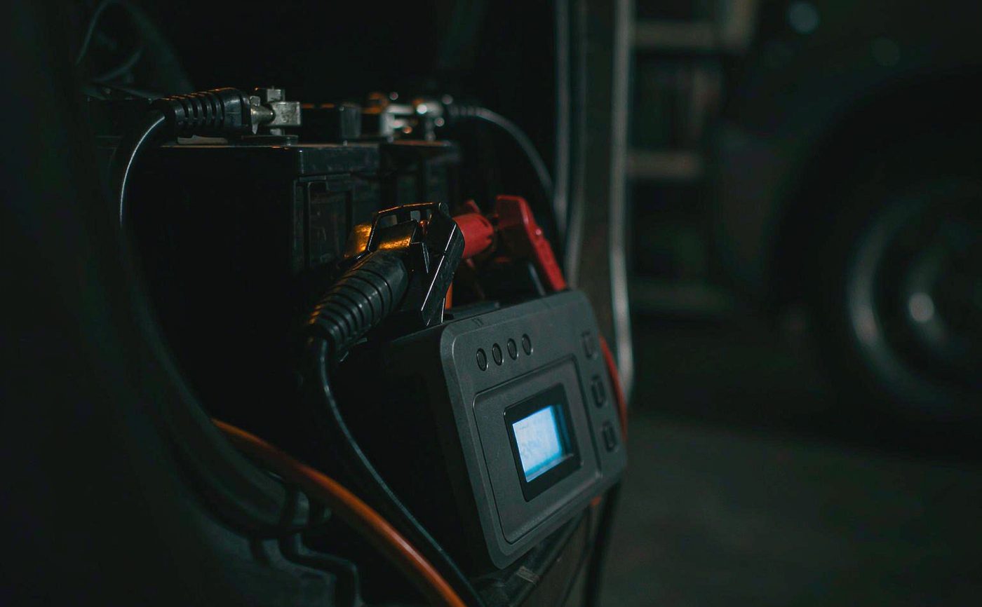 A jump starter connected to a car battery at night